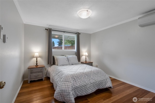 bedroom featuring baseboards, ornamental molding, wood finished floors, and a wall mounted air conditioner