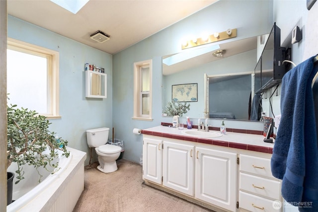 full bath featuring a relaxing tiled tub, toilet, lofted ceiling with skylight, and vanity