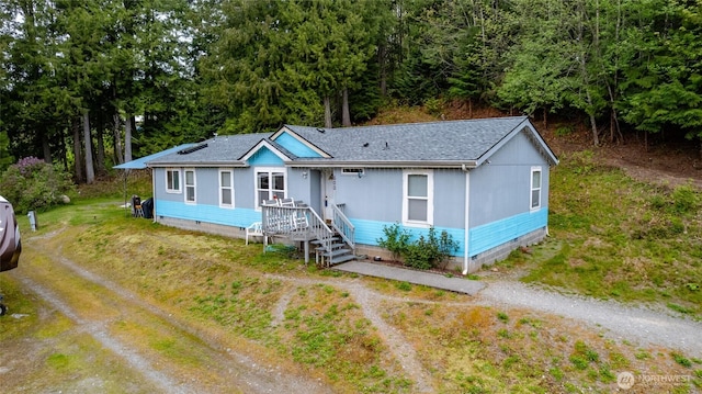 manufactured / mobile home featuring roof with shingles, dirt driveway, and crawl space