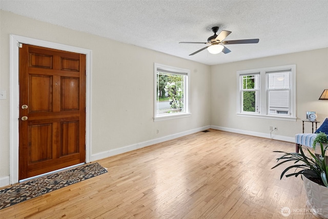 interior space featuring plenty of natural light, baseboards, ceiling fan, and wood finished floors