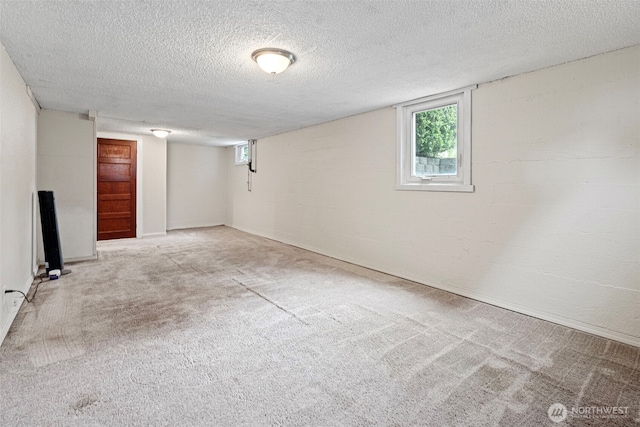 basement featuring a healthy amount of sunlight, carpet flooring, and a textured ceiling