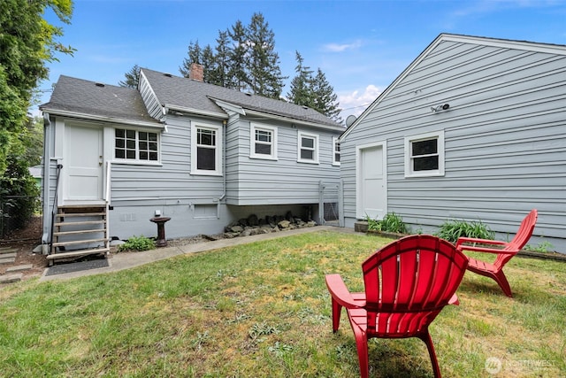 back of house with a chimney, a shingled roof, crawl space, entry steps, and a yard
