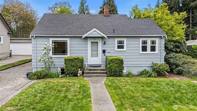 view of front of home with a chimney, an outdoor structure, roof with shingles, and a front lawn