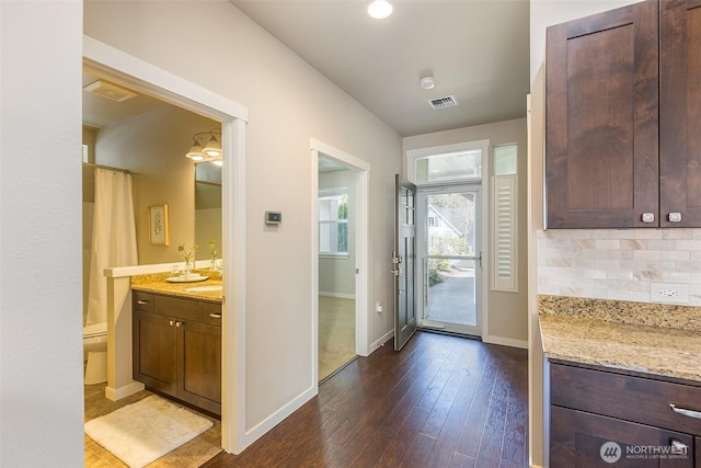 doorway with baseboards, dark wood-style floors, and visible vents