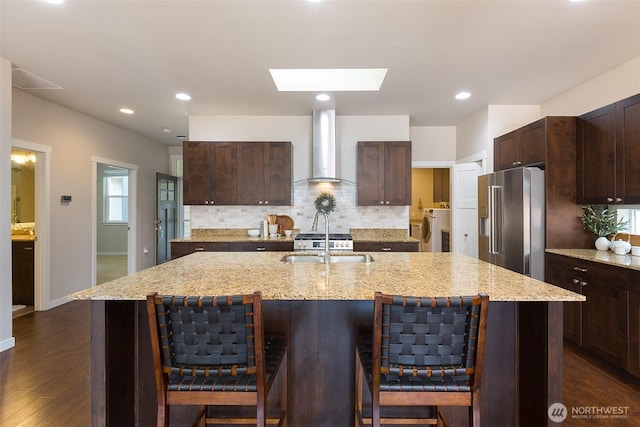 kitchen featuring decorative backsplash, washer / dryer, wall chimney range hood, high quality fridge, and a skylight