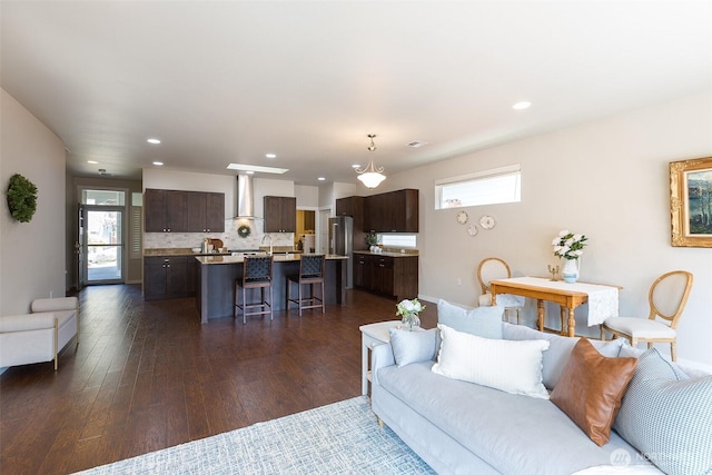 living area with recessed lighting, baseboards, and dark wood-type flooring