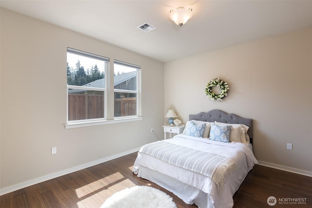 bedroom with baseboards, wood finished floors, and visible vents