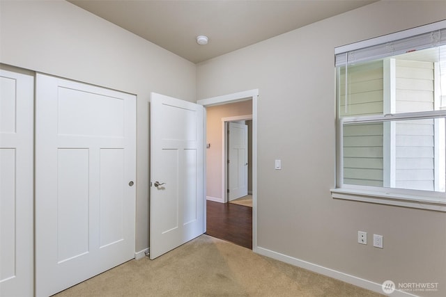 unfurnished bedroom featuring a closet, baseboards, and carpet flooring