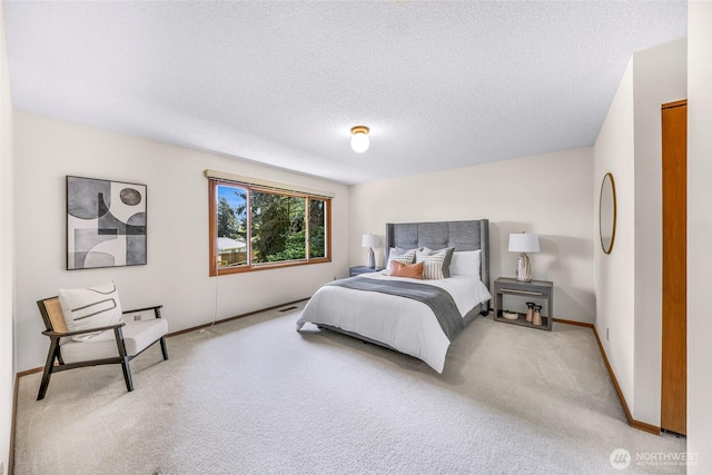bedroom featuring baseboards, light carpet, and a textured ceiling