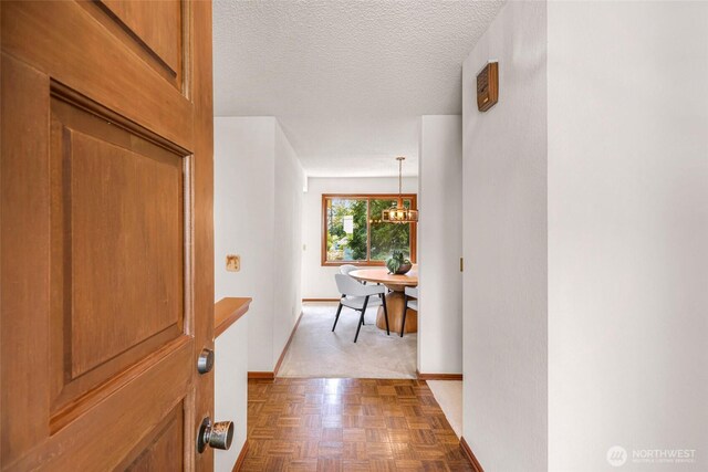 interior space featuring an inviting chandelier, baseboards, and a textured ceiling