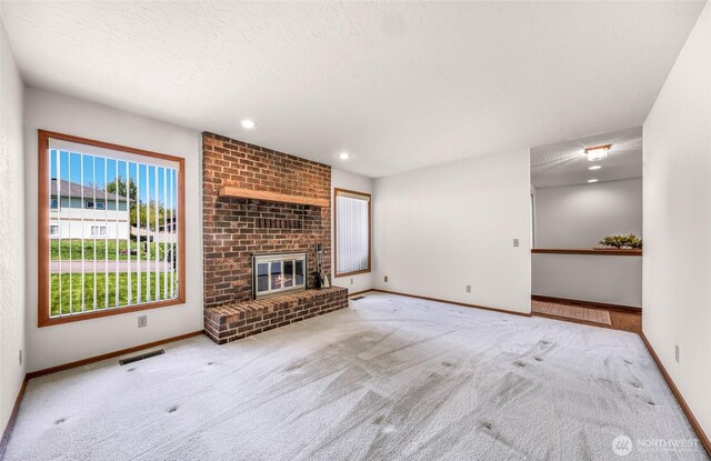 unfurnished living room featuring carpet floors, a textured ceiling, baseboards, and visible vents