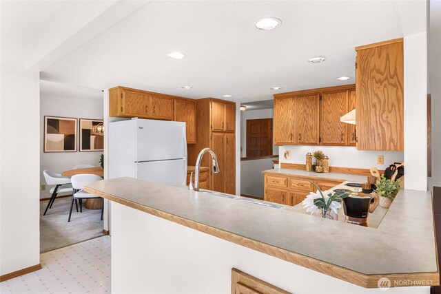 kitchen featuring a sink, recessed lighting, freestanding refrigerator, and a peninsula