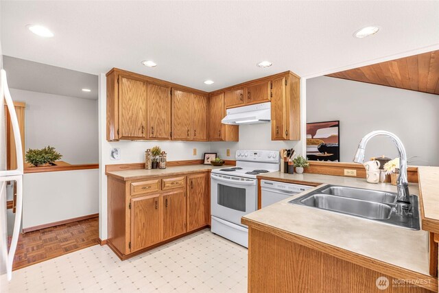 kitchen with white appliances, recessed lighting, light countertops, under cabinet range hood, and a sink