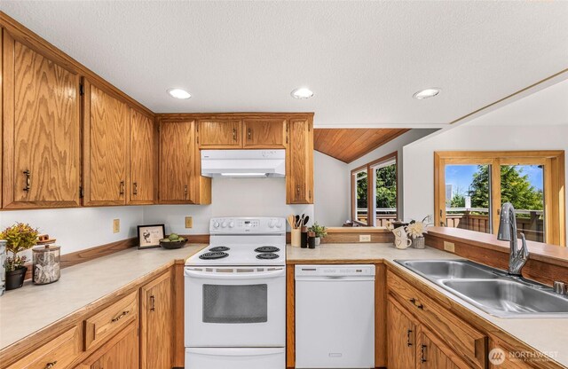 kitchen with a sink, white appliances, light countertops, recessed lighting, and under cabinet range hood