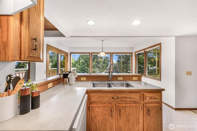 kitchen with light countertops, brown cabinets, a sink, and dishwasher