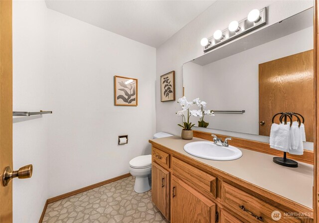 bathroom featuring toilet, tile patterned floors, baseboards, and vanity