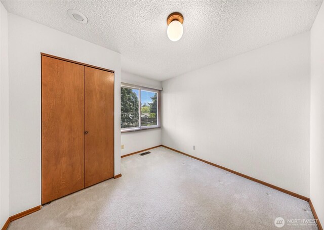 unfurnished bedroom with baseboards, carpet, and a closet