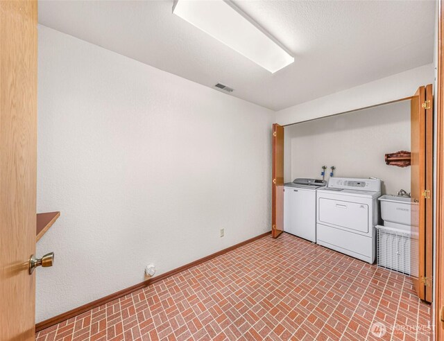 laundry room with baseboards, visible vents, brick patterned floor, and washer and dryer