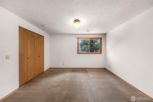 unfurnished bedroom with visible vents, carpet flooring, a textured ceiling, and a closet