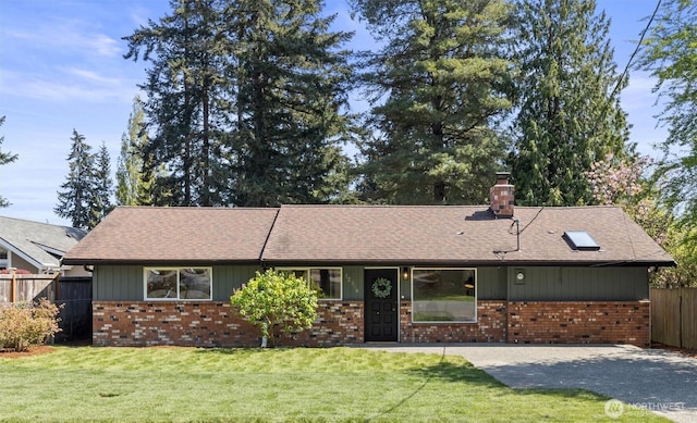 ranch-style home featuring fence, a shingled roof, a front lawn, brick siding, and a chimney