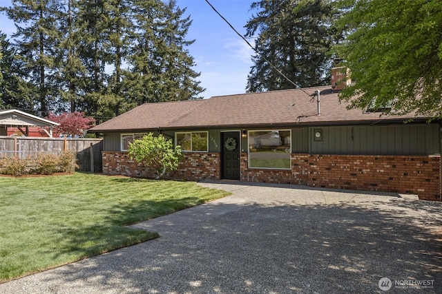 ranch-style home featuring brick siding, fence, a chimney, and a front yard