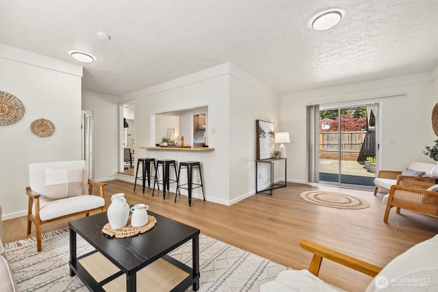 living area with baseboards, a textured ceiling, and wood finished floors