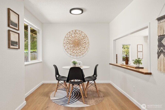 dining area featuring baseboards and light wood-style flooring
