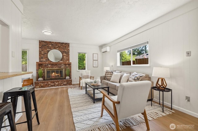 living area with an AC wall unit, plenty of natural light, and wood finished floors