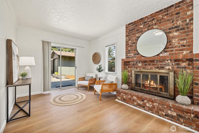 living room featuring plenty of natural light, a textured ceiling, wood finished floors, and a fireplace