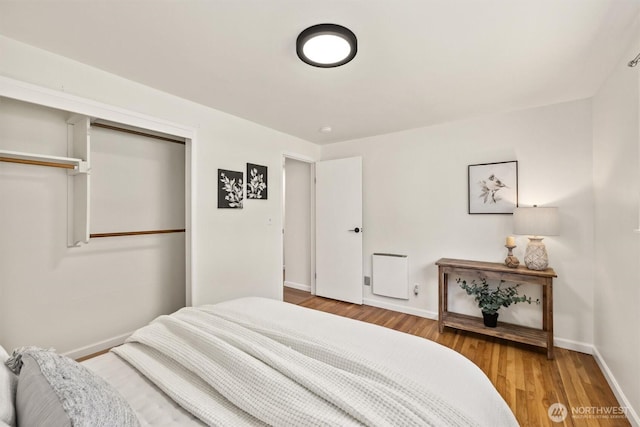 bedroom with baseboards, wood finished floors, and a closet