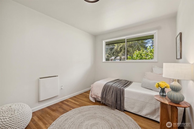 bedroom featuring baseboards, heating unit, and wood finished floors