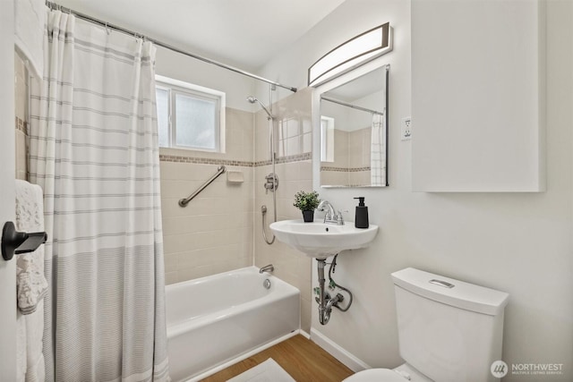 bathroom with baseboards, shower / bathtub combination with curtain, wood finished floors, and toilet