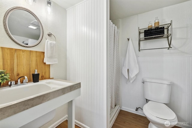 bathroom featuring a sink, a shower with shower curtain, wood finished floors, and toilet