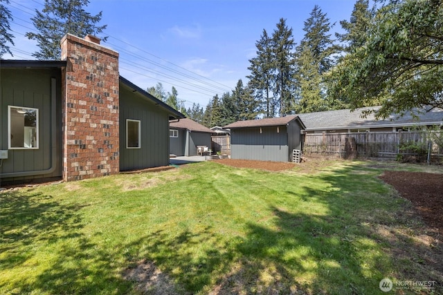 view of yard featuring fence, an outdoor structure, and a shed