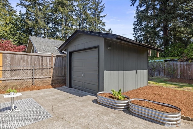detached garage with concrete driveway and fence