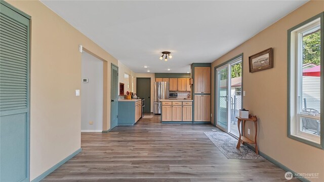 kitchen with wood finished floors, stainless steel appliances, light countertops, and baseboards