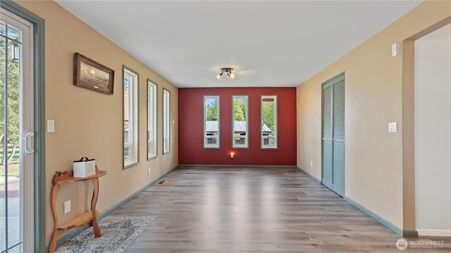unfurnished room with baseboards, wood finished floors, and a healthy amount of sunlight