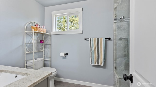 bathroom featuring vanity, toilet, a shower, baseboards, and wood finished floors