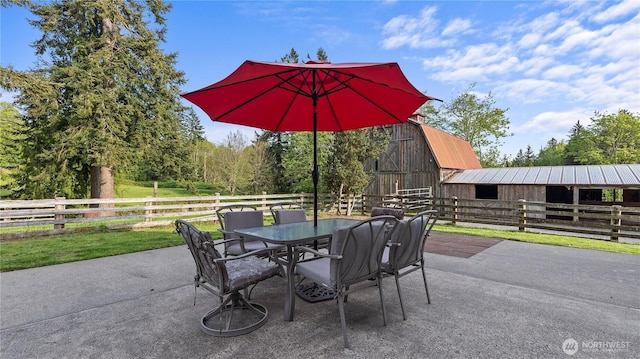 view of patio / terrace with a barn, outdoor dining area, an exterior structure, and an outbuilding