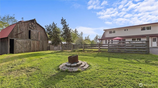 view of yard with fence, an outdoor structure, an outdoor fire pit, and a barn