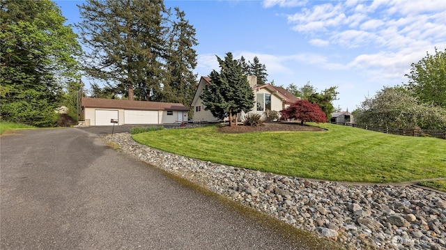 view of front of home with a garage, a chimney, an outdoor structure, and a front yard