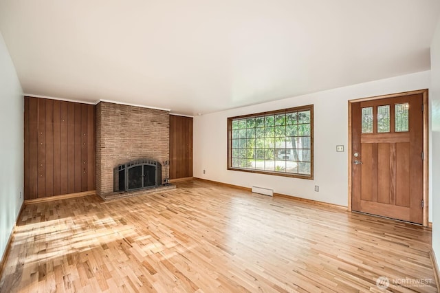 unfurnished living room with baseboards, a baseboard radiator, a brick fireplace, and light wood-style flooring