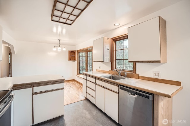 kitchen with an inviting chandelier, pendant lighting, light countertops, a sink, and stainless steel appliances
