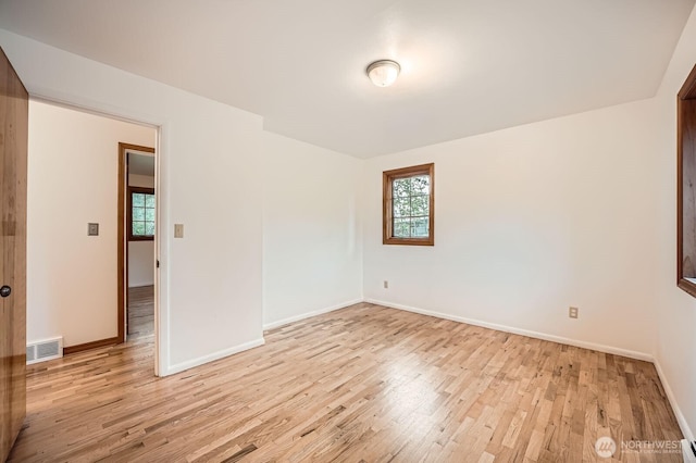 unfurnished room with visible vents, light wood-style flooring, plenty of natural light, and baseboards