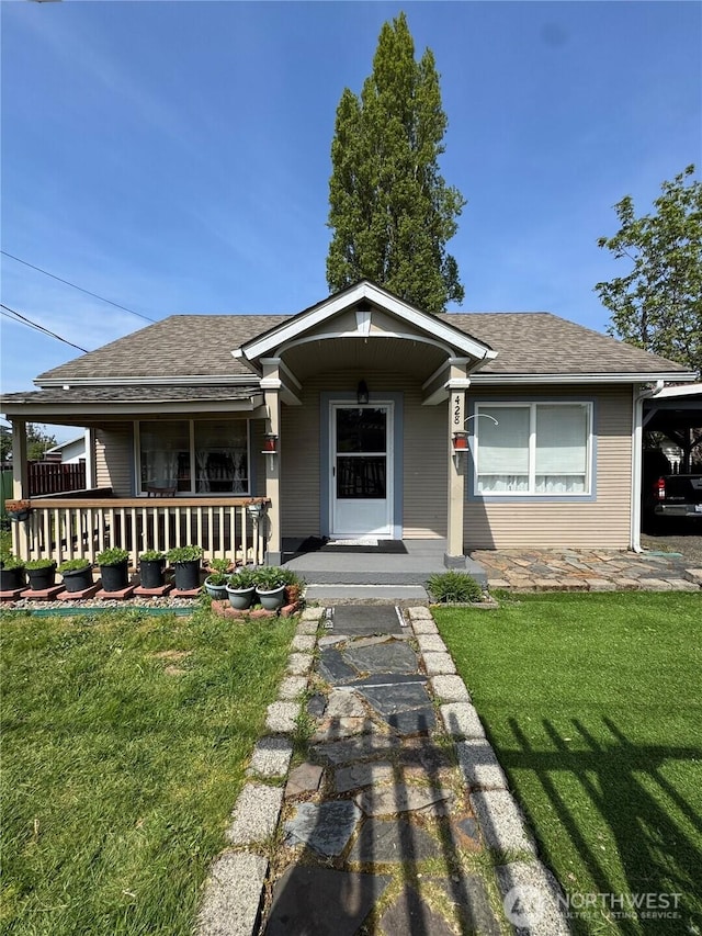 view of front of home featuring covered porch, a front yard, and a shingled roof