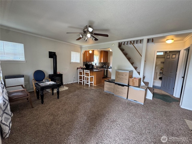 living room with ornamental molding, a wood stove, and a ceiling fan