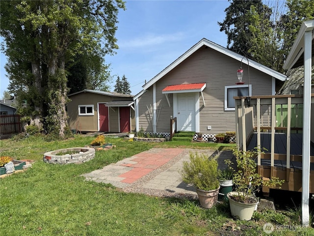 view of front of house with an outdoor structure, an outdoor fire pit, and a front yard