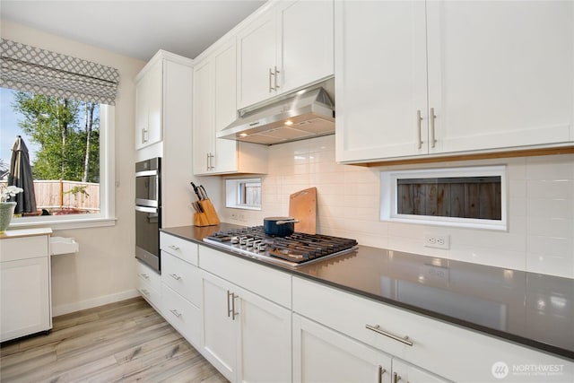 22125 Jameson Ave NW, Poulsbo, WA 98370 - kitchen featuring under cabinet range hood, stainless steel appliances, tasteful backsplash, baseboards, and white cabinetry