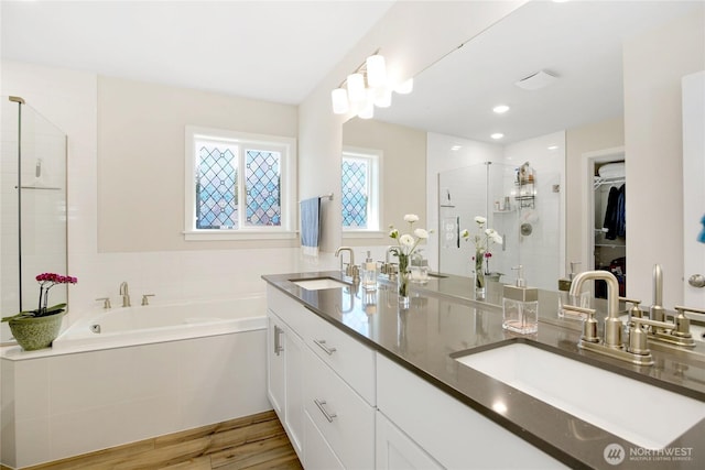 22125 Jameson Ave NW, Poulsbo, WA 98370 - bathroom with a stall shower, a bath, double vanity, a walk in closet, and wood finished floors