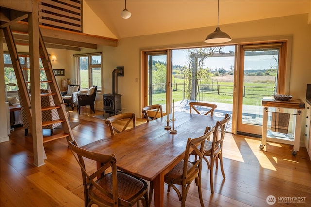 dining area featuring a wood stove, light wood-style floors, and lofted ceiling